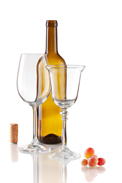 静物用空酒瓶，两个不同形状的玻璃杯，软木塞和小葡萄串。工作室拍摄的自然反射在白色背景。图片下载