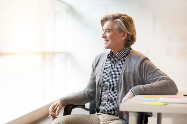 成熟的商人坐在商务办公室里，看着窗户图片下载