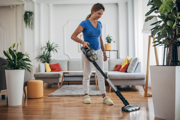 一位女士正在用无绳吸尘器吸尘客厅图片下载
