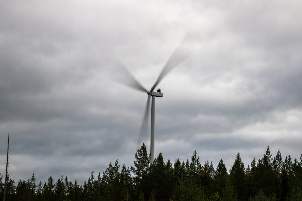 旋转的风力涡轮机对着多云的天空，长镜头曝光。图片下载