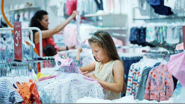 在商店里购物。儿童服装。女孩，小孩，在商店里挑选东西。小fashion-girl。购物狂。在商店里乏味地购物图片下载