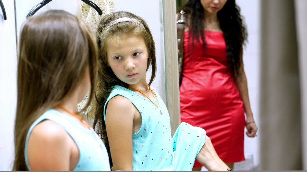 在商店里乏味的购物。累了，伤心的孩子，女孩，手里拿着一堆东西，在商店里等着父母。图片下载