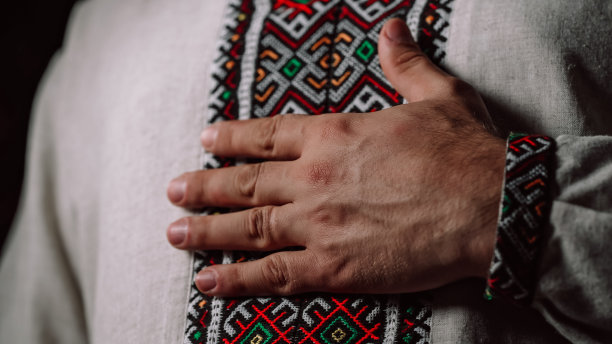 男子在vyshyvanka衬衫上展示刺绣装饰的几何细节。民族服饰-刺绣衬衫，质地，图案，民俗，手工工艺针线活图片下载