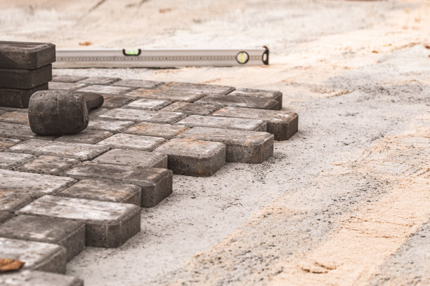 铺设铺路板特写。路面、施工。人行道上修复。工人在铺设石板。在城市公园的花园里铺瓷砖。手工固定镶嵌铺装板图片下载