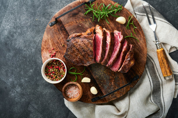 牛排。切片烤肉牛排纽约或Striploin与香料迷迭香和胡椒粉放在黑色大理石板老石头灰色背景。前视图。模拟。图片下载