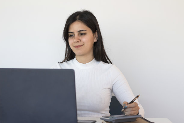 年轻女子在电脑前做笔记图片下载