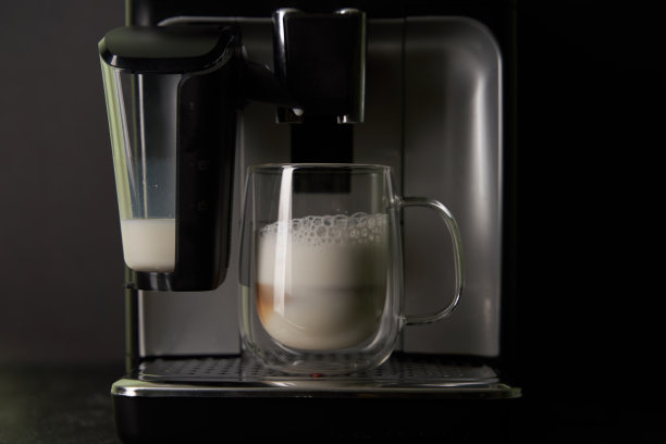 刚煮好的卡布奇诺从咖啡机里倒进玻璃杯里。图片下载