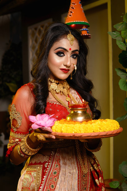 漂亮的年轻印度女孩穿着传统的纱丽，黄金珠宝和手镯在工作室照明室内拿着盘子的宗教祭品。印度文化、宗教和时尚。图片下载