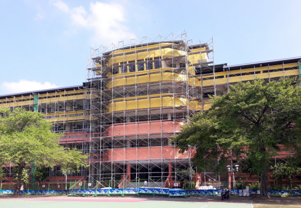 搭建的房子。学校。建筑。高层建筑,改造。用旧的屋顶和地面材料搭建脚手架。正在施工的建筑物上盖着脚手架。地面的角度图片下载