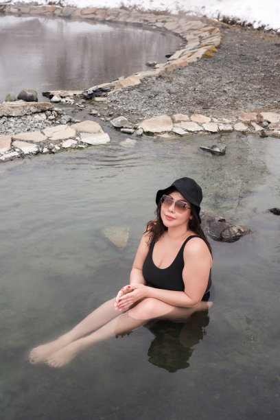 曲线丰满的身材的女人在黑色连体泳衣坐在温泉度假村的户外游泳池图片下载