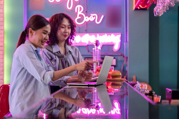 Revisualizing灵活的工作。一名女商人下班后在鸡尾酒吧用笔记本电脑与同事们商讨工作图片下载