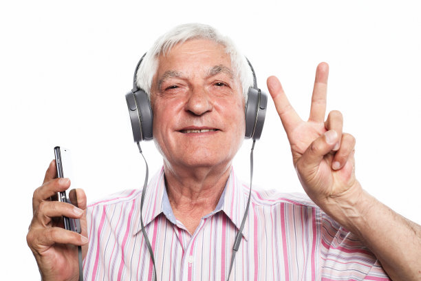 英俊的老人正在用手机听音乐，微笑着，在白色的背景上展示v字手势图片下载