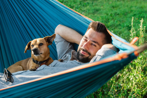 迷人的欧洲人的肖像吊床上与可爱的昏昏欲睡的狗。图片下载