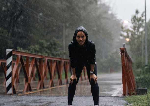 亚洲女士在雨中奔跑，她很累图片下载