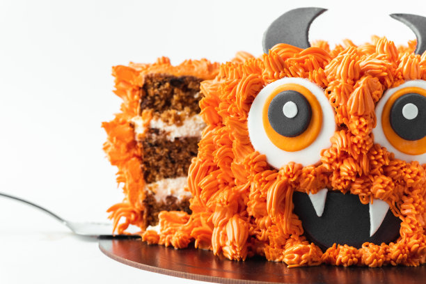 白色背景上的怪物主题蛋糕。万圣节蛋糕，橙色蓬松的奶油奶酪糖霜隔离在白色图片下载