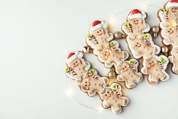姜饼人配节日糖衣。白色背景上有花环灯的圣诞饼干。新年快乐。图片下载
