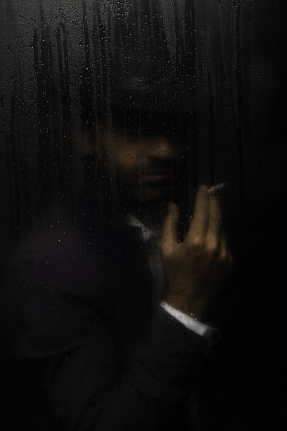 神秘男子的肖像，戴着帽子，站在湿玻璃后面图片下载