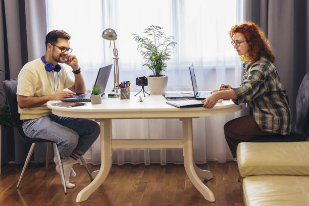年轻的千禧一代夫妇在家工作。自由职业和远程工作的概念图片下载