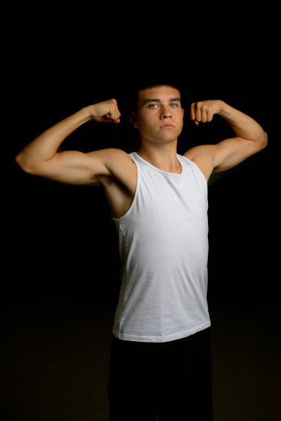 19岁的十几岁的男孩在展示他的手臂肌肉图片下载