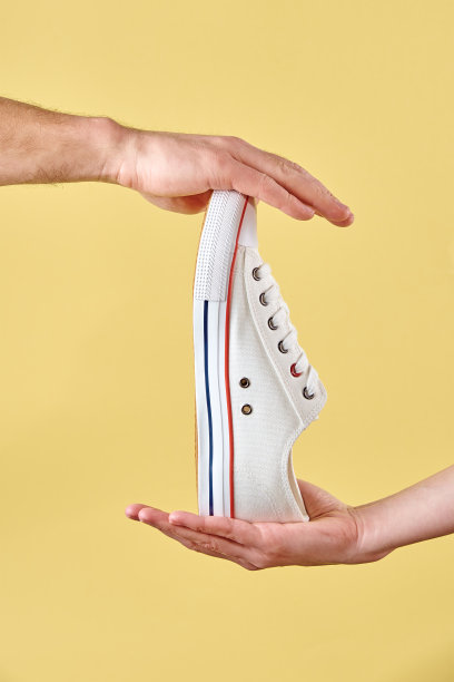 在黄色背景的时髦时髦的鞋子在手中图片下载
