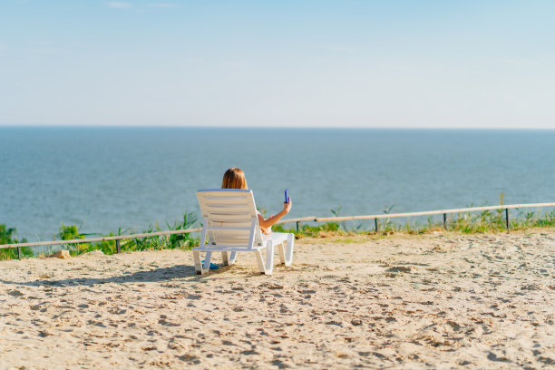 一个女人用你的手机拍照，在躺椅上晒日光浴图片下载