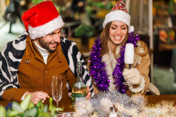 一对快乐的年轻夫妇坐在咖啡馆里，喝着酒敬酒。图片下载
