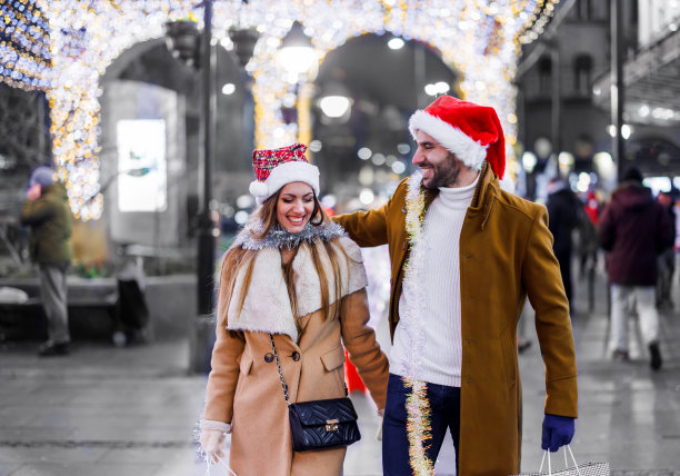 一对年轻夫妇在节日里背着纸袋走路。图片下载