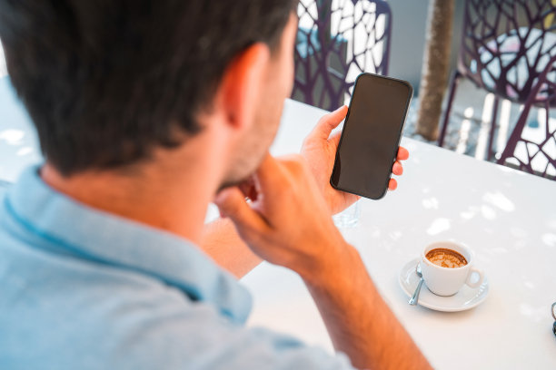 年轻英俊的男子用他的智能手机阅读电子邮件图片下载