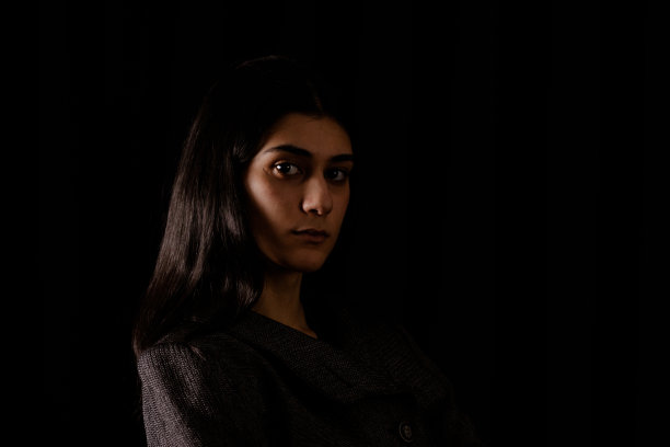 高对比度深色背景下的年轻女子肖像图片下载