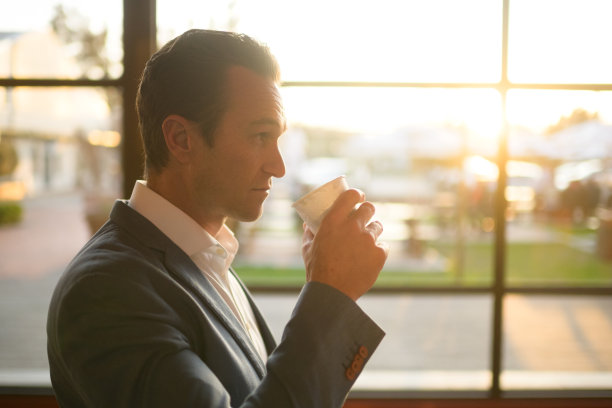侧视图侧面肖像的商人有一个热饮在一次性杯与日落图片下载