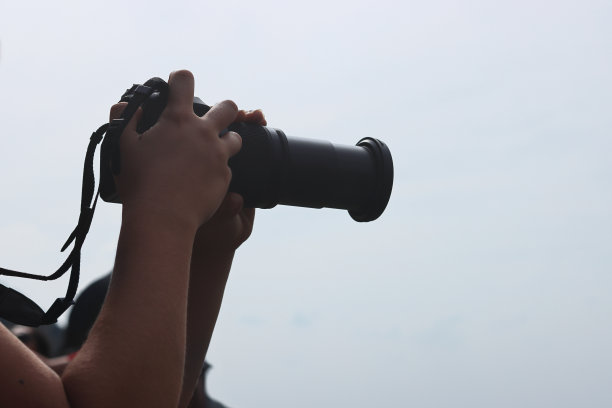 年轻女子手里拿着数码相机。在镜头背后，摄影师正在拍摄自然景观。天空背景。图片下载