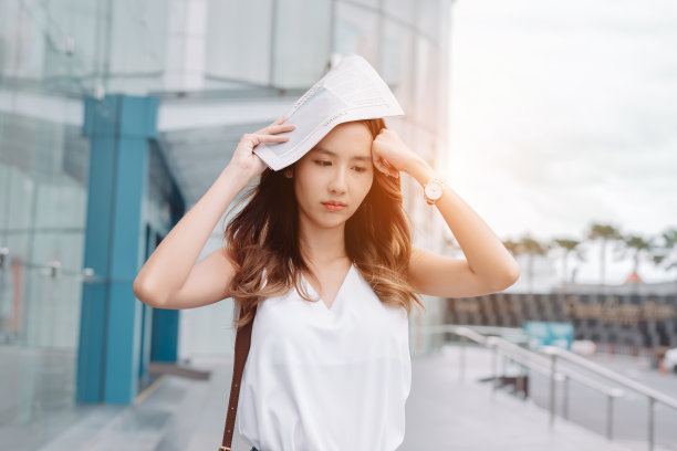 亚洲女商人的面部皮肤受到来自现代城市办公室附近明亮阳光的紫外线攻击，防晒霜，防晒霜的概念。图片下载