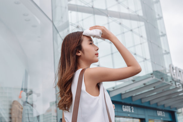 亚洲女商人的面部皮肤受到来自现代城市办公室附近明亮阳光的紫外线攻击，防晒霜，防晒霜的概念。图片下载