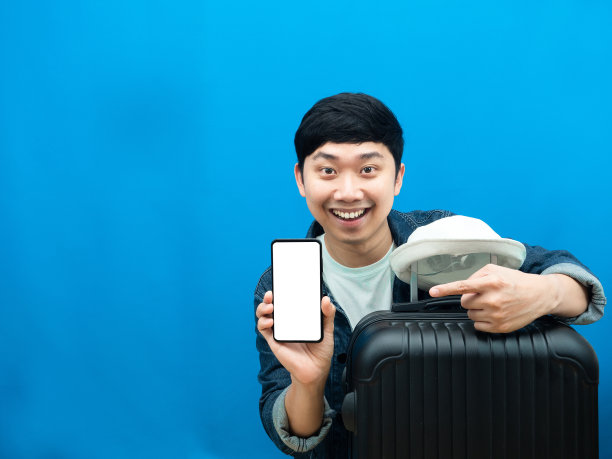 男人带着行李箱为假期展示手机快乐的笑容蓝色背景图片下载
