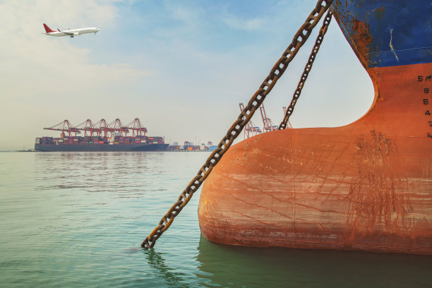 在集装箱港口上空飞行的飞机。图片下载