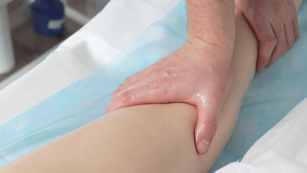 按摩师的手按摩女性腿部的肌肉。图片下载