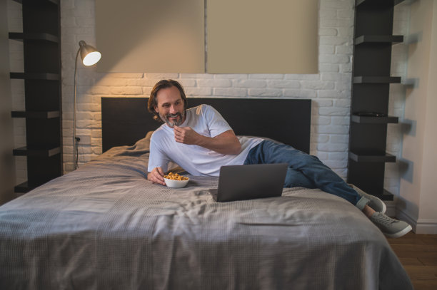 男人下班后休息，一边吃零食一边上网看东西图片下载