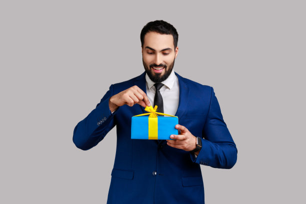 男子打开礼品盒，打开节日礼物，拉丝带，看礼物。图片下载