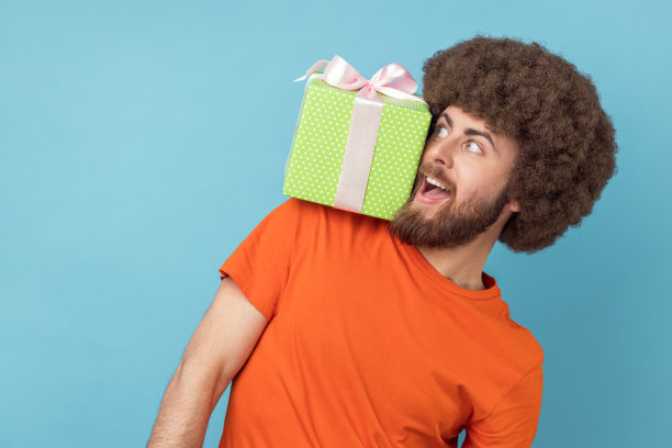 滑稽的傻男人站在他的肩膀上，礼物盒，看向别处，玩得很开心。图片下载