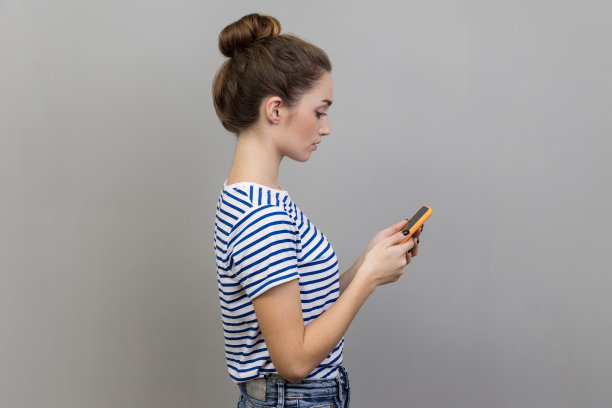 侧面严肃的女人拿着智能手机，打字信息或浏览网络，使用手机。图片下载