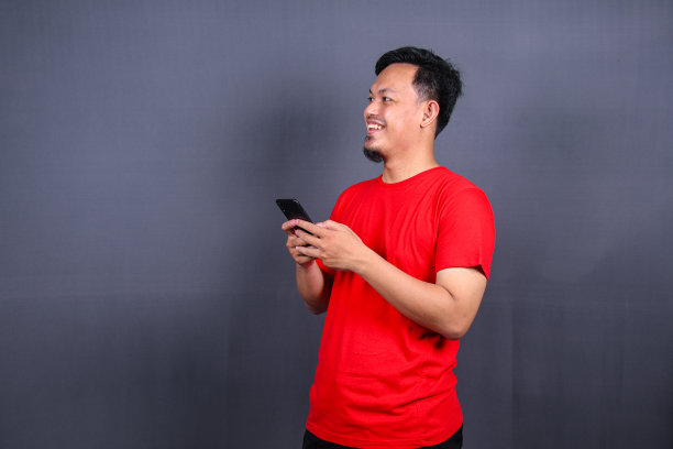 一个年轻快乐的亚洲人使用手机的肖像图片下载