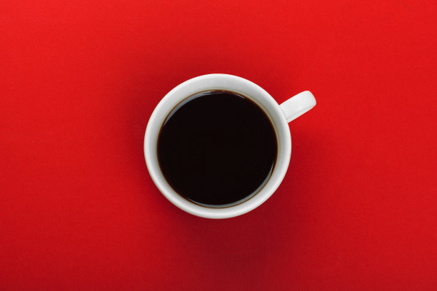 有红色背景的咖啡豆的咖啡杯。图片下载