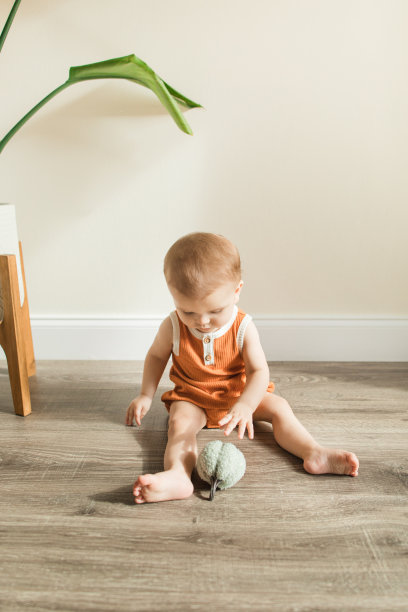 一个有12个脚趾的9个月大的流行病男婴穿着秋天的橙色衣服，在2022年秋天玩毛绒玩具南瓜图片下载