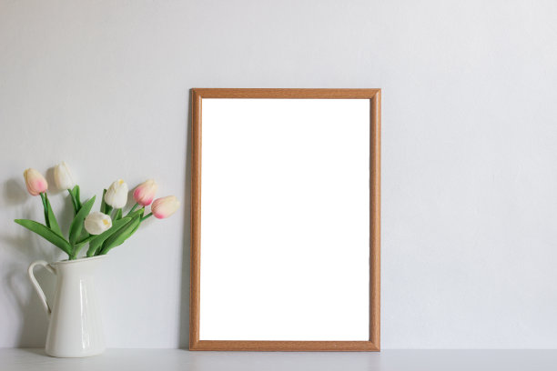 木质相框和白色墙壁上的郁金香，自然光。图片下载