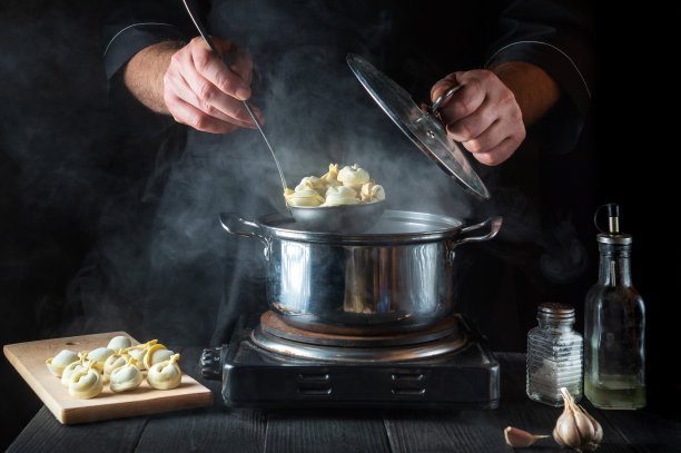 厨师在餐厅厨房用平底锅准备意大利饺子。一个厨师工作时的手特写。做一顿美味的午餐或早餐。图片下载