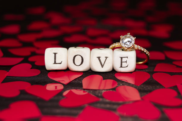 “爱”这个词来自木头立方体和深色木头上的结婚戒指。情人节的背景图片下载