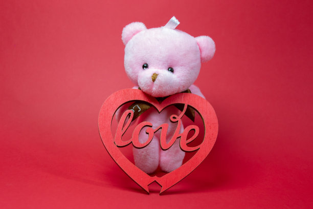 泰迪熊抱着一颗心，留白文字，红色背景，情人节的概念图片下载