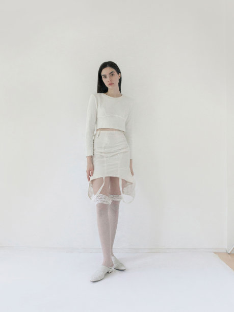 美丽的年轻苗条的褐发女子穿着总白色长袖露脐上衣设计师迷你裙网袜时尚模特全身工作室肖像在光背景图片下载