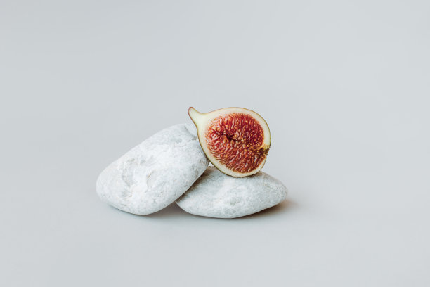 成熟的无花果和灰色背景上的石头。最小的概念。图片下载