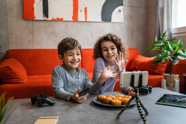 男孩和女孩两个兄弟姐妹，哥哥妹妹在手机上制作视频博客为在线互联网博客从他们的家最喜欢的玩具评论创建和分享内容的社交网络复制空间图片下载